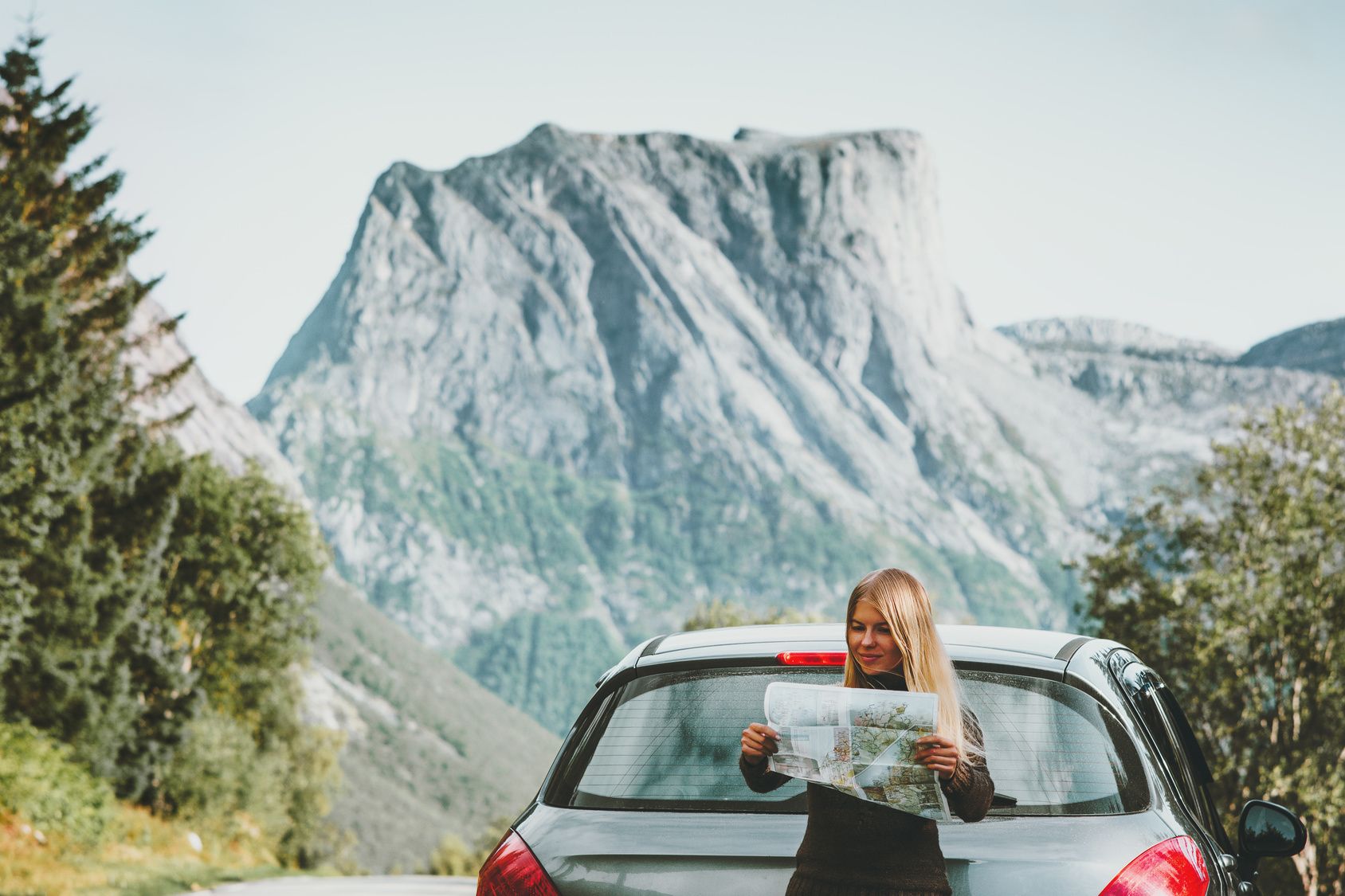 blond woman reads a map in front of mountains