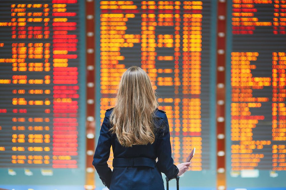 Woman stands in airport seeing all flights are canceled due to COVID-19