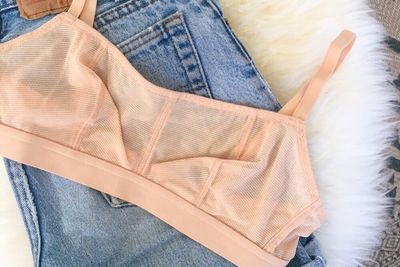 Lively pink bralette laid on top of a pair of blue jeans