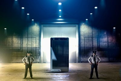 two security gaurds stand beside a giant smart phone