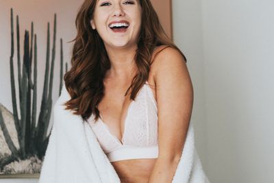 A redheaded woman in white undergarments laughs to the camera